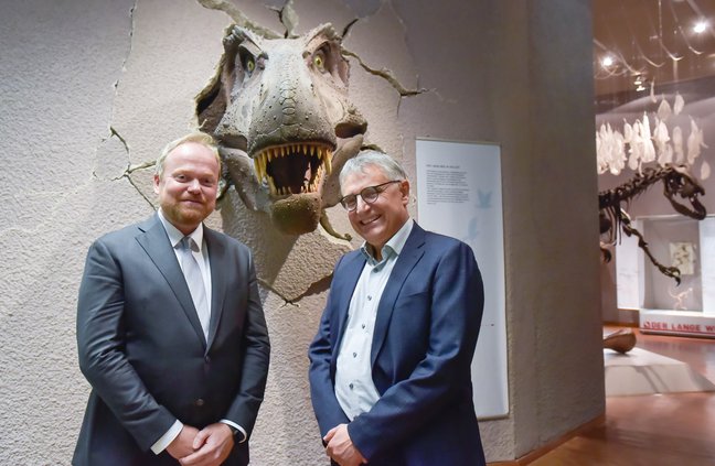 Museumsdirektor Lars Krogmann und Staatssekretär Arne Braun vor einem Tyrannosaurus rex Modell