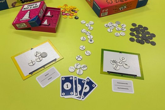 Ein auf einem Tisch ausgebreitetes Spiel mit Karten und verschiedenen Symbolplättchen