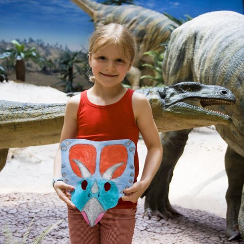 Kind mit bemalter Maske vor Plateosaurus-Modell