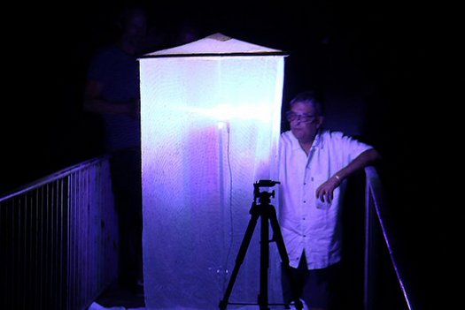 Wissenschaftler neben eine Lichtfalle für Insekten bei Nacht.