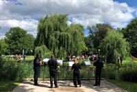 Vier Personen musizieren an einem See im Rosensteinpark vor Publikum