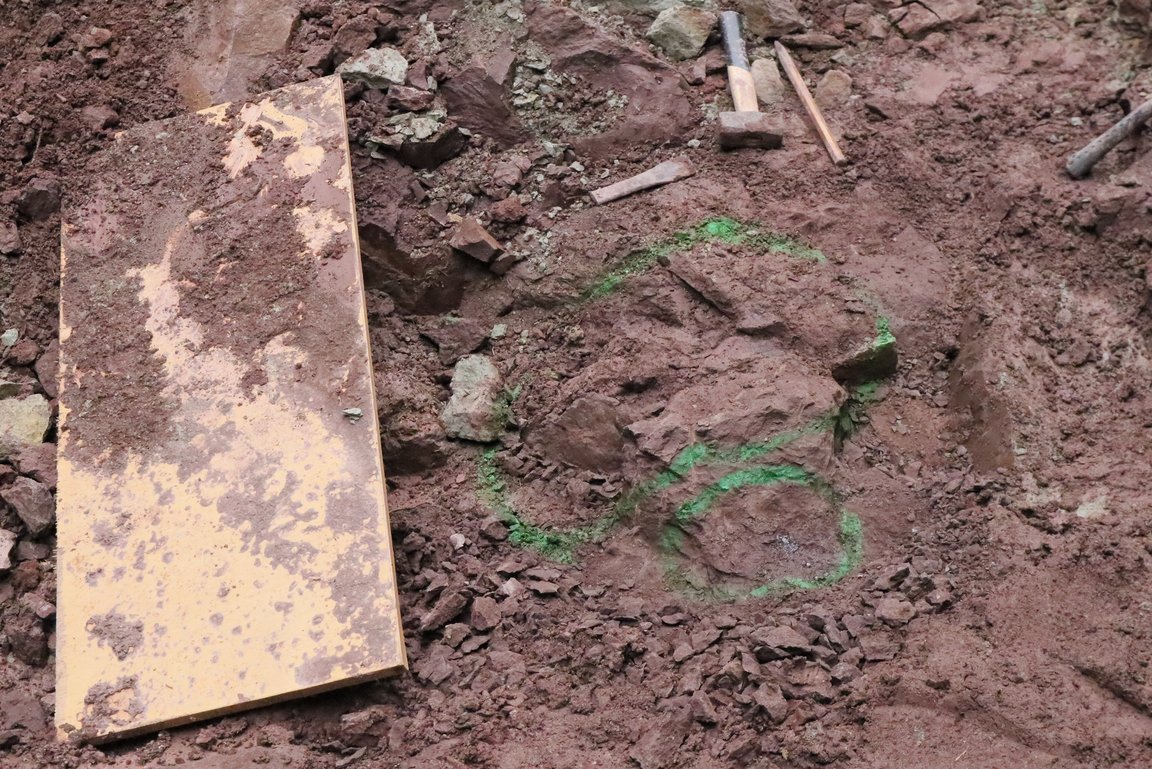 Grüne Sprühfarbe bildet einen Kreis um ein Fundstück in rotem Gestein.