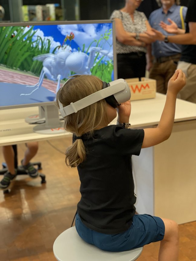 Kind mit VR-Brille vor einem Monitor.