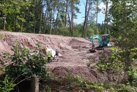 Bagger und mehrere Personen in Warnwesten in einer Ausgrabungsstelle