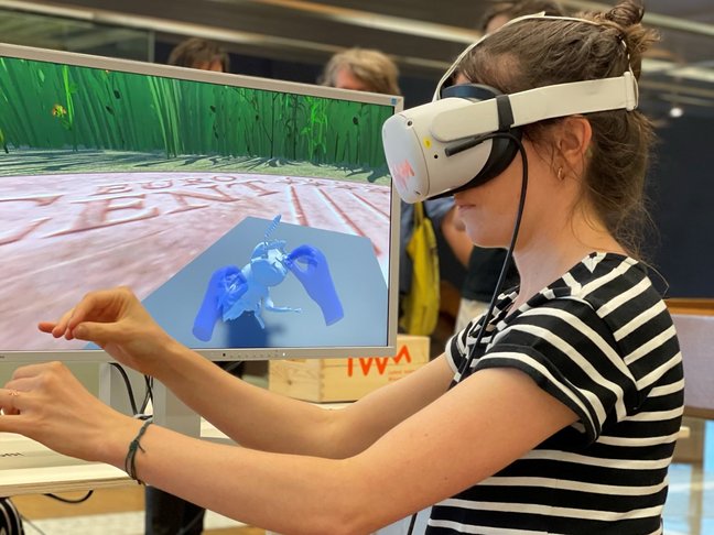 Person mit aufgesetzter VR-Brille vor einem Monitor.