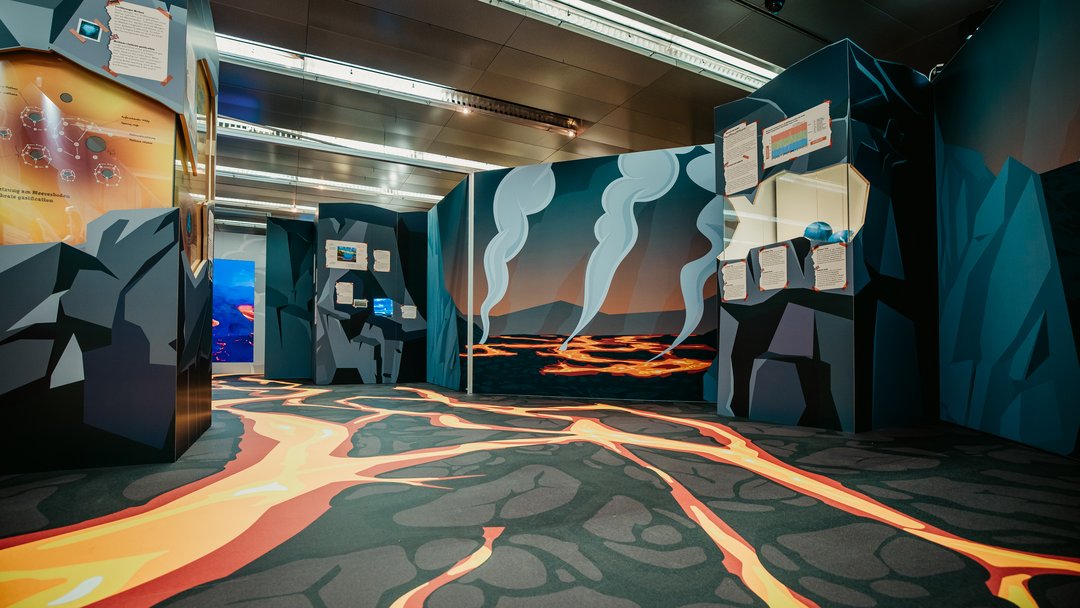 Blick in den ersten Ausstellungsraum mit gezeichneter auströmender Lava und Rauchwolken