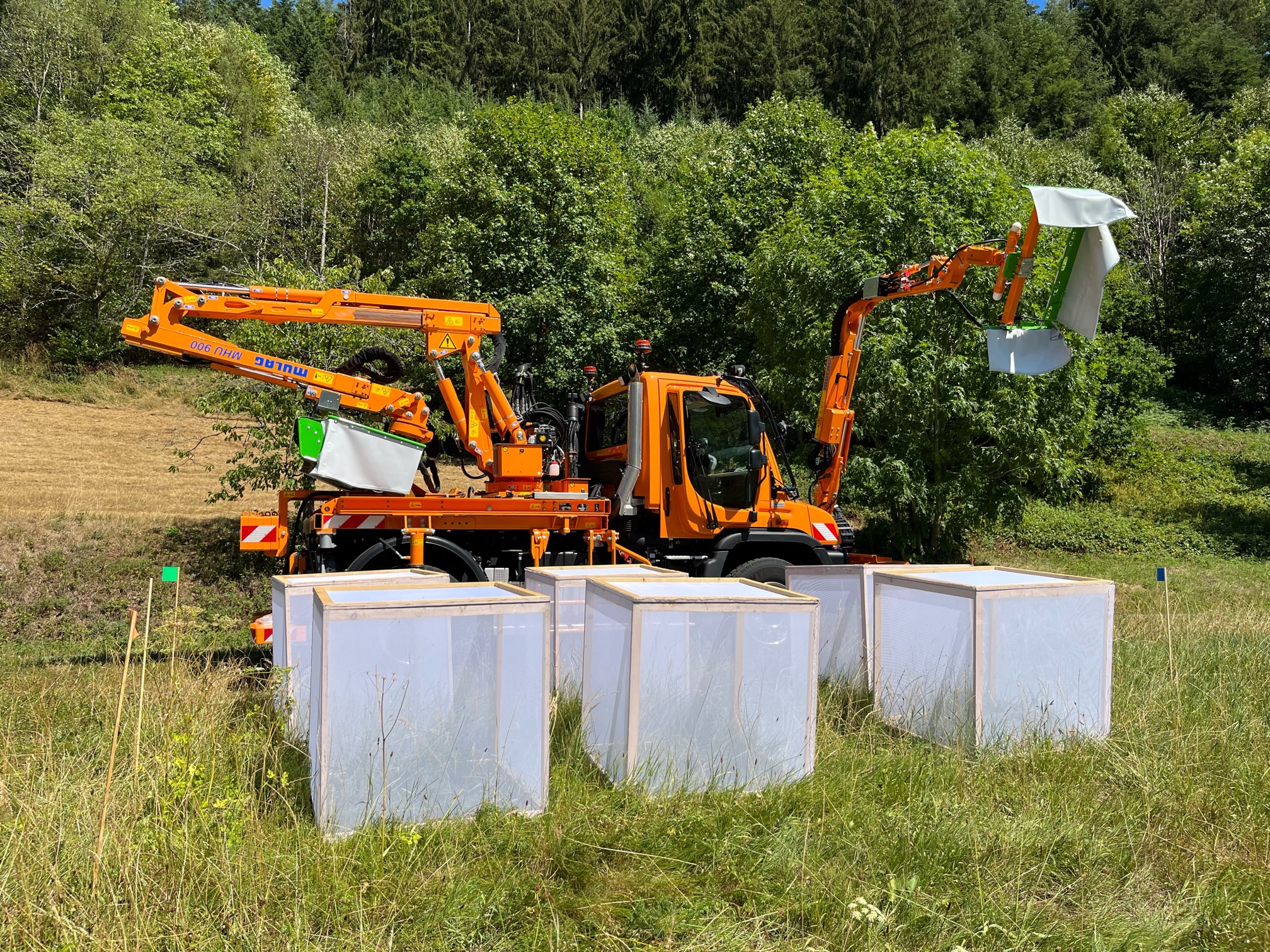 Insektenfreundlicher Mäher mit Insektenscheuche und Käfige auf einer Wiese