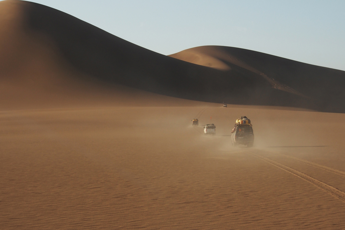 Expedition Wüste Lut H. Rajaei zugeschnitten Vier Geländewagen in der Wüste vor Sanddünen.