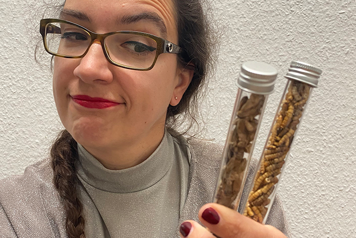 Frau hält zwei Glasröhrchen gefüllt mit essbaren Insekten.