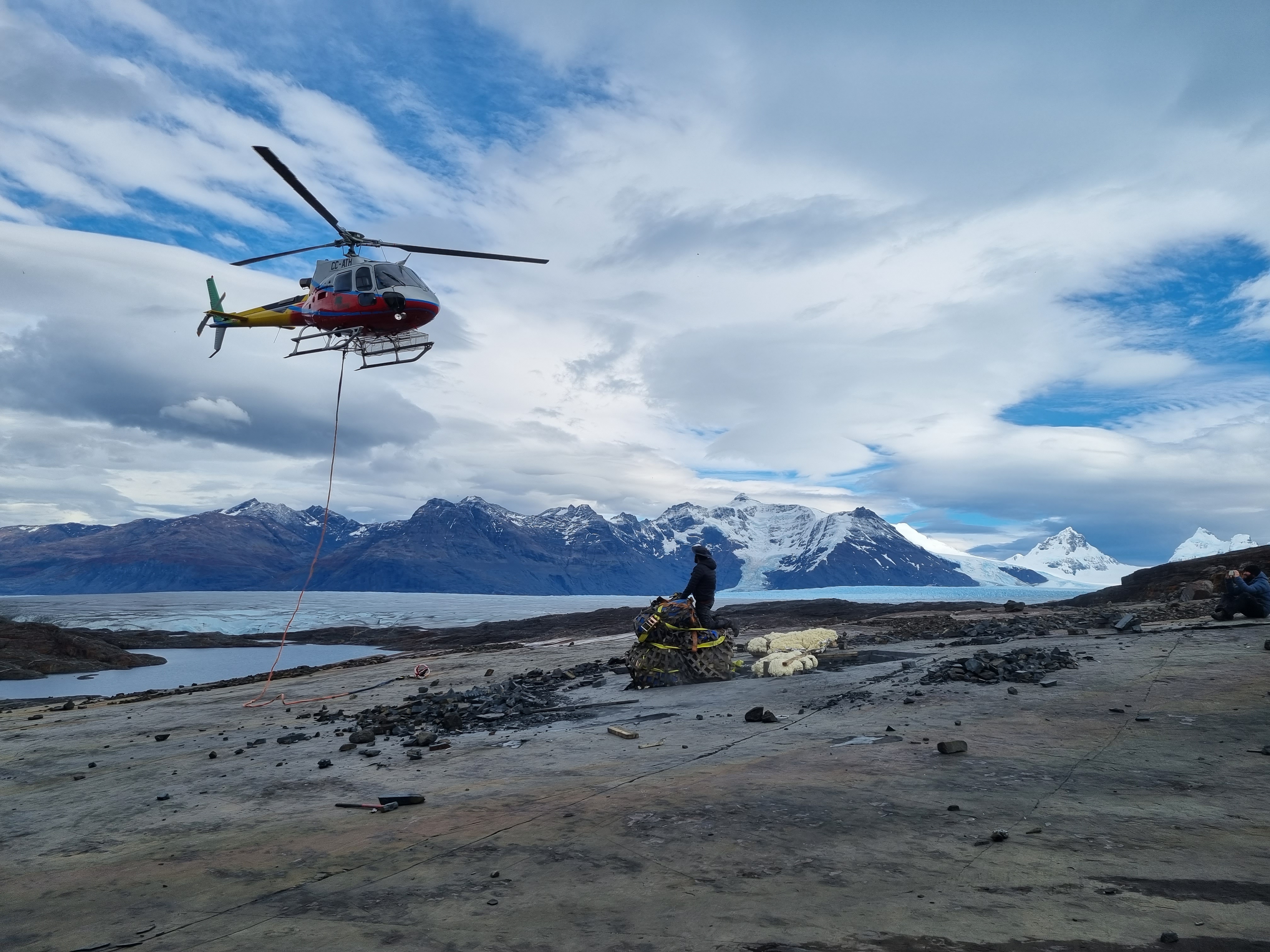 Transporthubschrauber in der Luft über einer Ladung Fossilien vor dem Tyndall-Gletscher